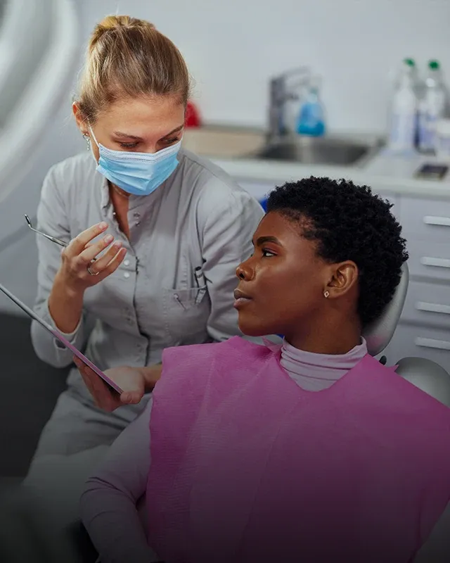 A dental professional consulting a patient in a dental exam chair